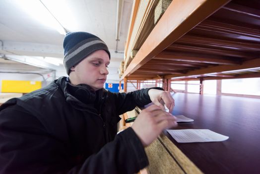 young man carpenter using pen while writing a receipt  in big modern carpentry