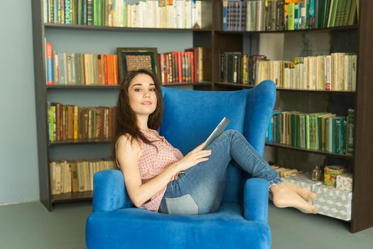 Leisure, people and home concept - Happy relaxed woman in home library.
