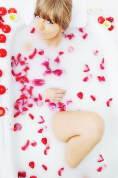 woman beauty spa and wellness treathment with red flower petals in bath