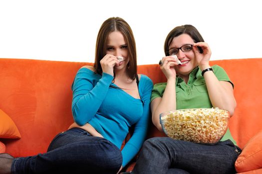 female friends eating popcorn and watching tv at home on orange sofa isolated on white