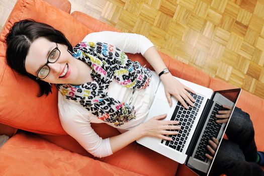 young business woman in casual clothes working on laptop computer on orange sofa isolated on white