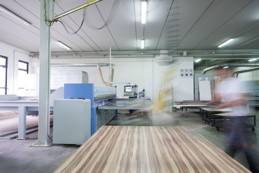 Young worker works in a factory for the production of wooden furniture