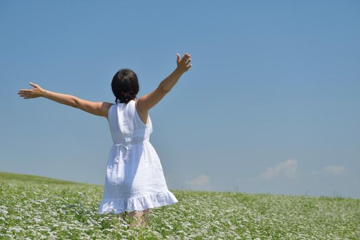 Young happy woman in green field with blue sky in background