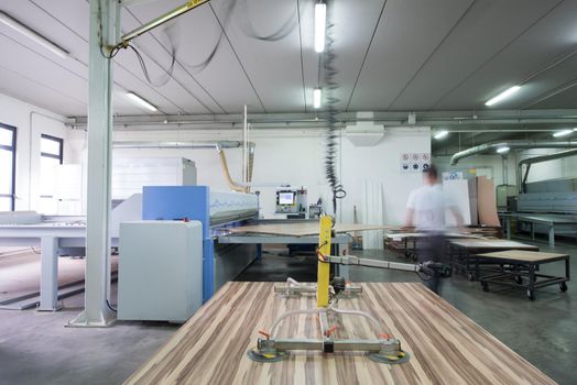 Young worker works in a factory for the production of wooden furniture
