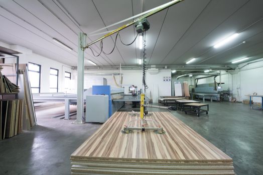 Young worker works in a factory for the production of wooden furniture