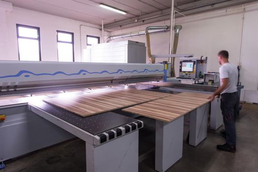Young worker works in a factory for the production of wooden furniture