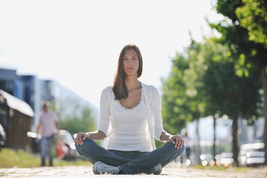 beautiful young woman meditating and exercise yoga in lotus position at street at beautiful sunny day with blured background