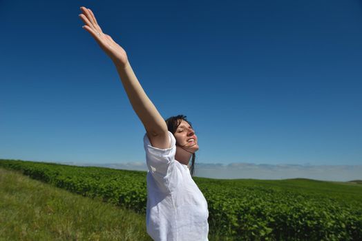 Young happy woman in green field with blue sky in background