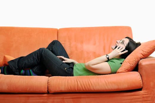 young woman on orange sofa talking by phone isolated on white in studio