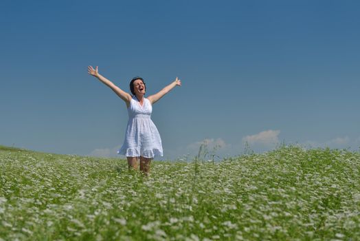 Young happy woman in green field with blue sky in background