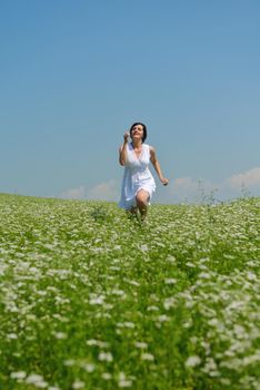 Young happy woman in green field with blue sky in background