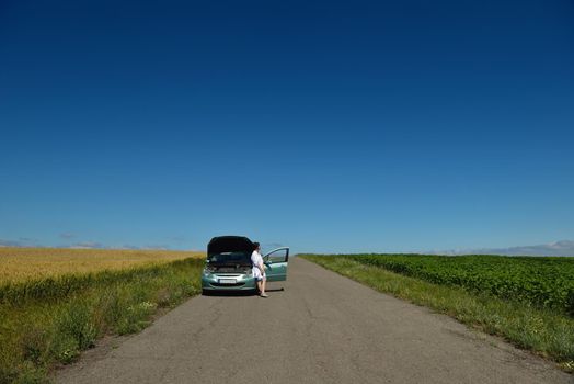portrait of young beautiful woman with broken car outdoor
