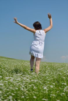 Young happy woman in green field with blue sky in background