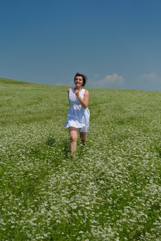 Young happy woman in green field with blue sky in background