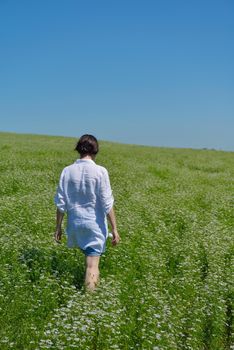 Young happy woman in green field with blue sky in background