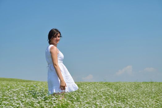 Young happy woman in green field with blue sky in background