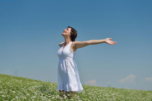 Young happy woman in green field with blue sky in background