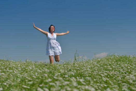 Young happy woman in green field with blue sky in background