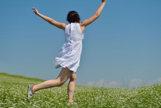 Young happy woman in green field with blue sky in background