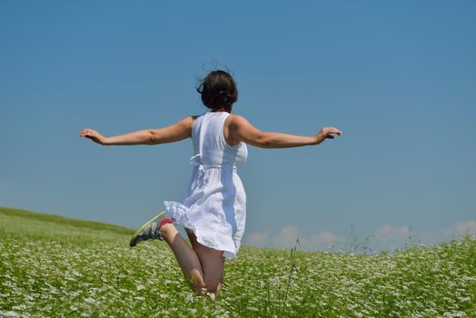 Young happy woman in green field with blue sky in background