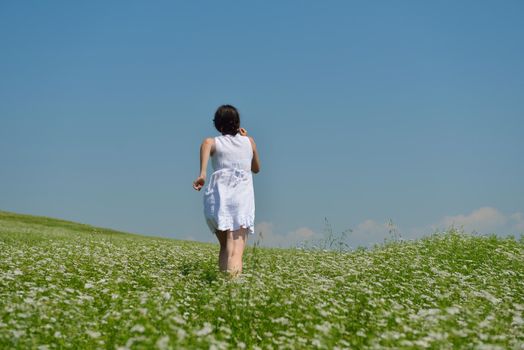 Young happy woman in green field with blue sky in background