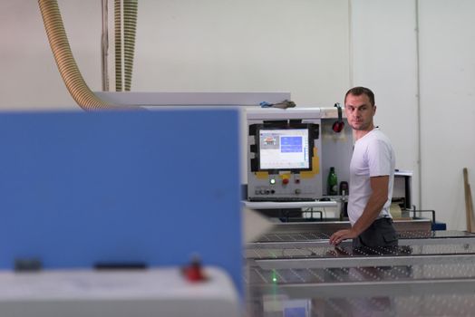 Young worker works in a factory for the production of wooden furniture