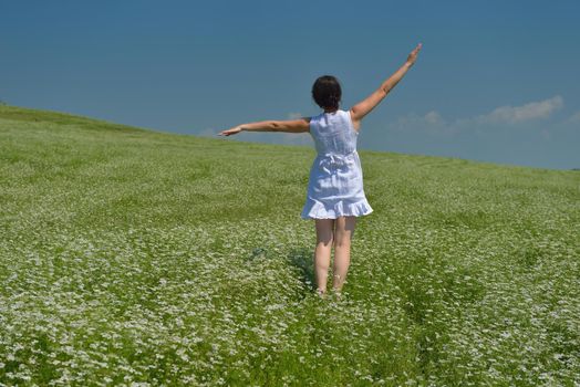 Young happy woman in green field with blue sky in background