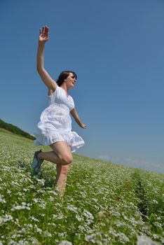 Young happy woman in green field with blue sky in background