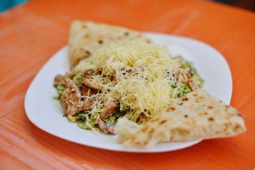 woman eat tasty chicken salad with fresh vegetables and cheese in retro kitchen