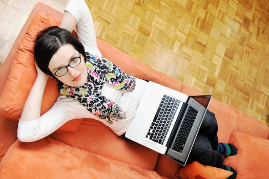 young business woman in casual clothes working on laptop computer on orange sofa isolated on white