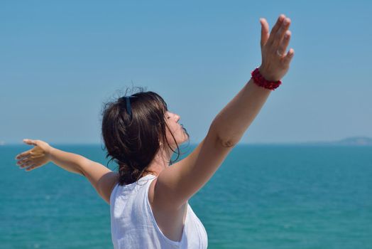 Happy  young woman with spreading arms, blue sky with clouds in background  - copyspace