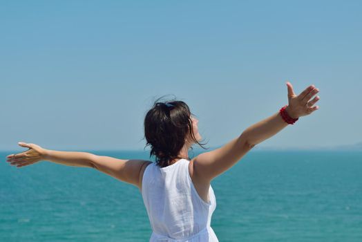 Happy  young woman with spreading arms, blue sky with clouds in background  - copyspace