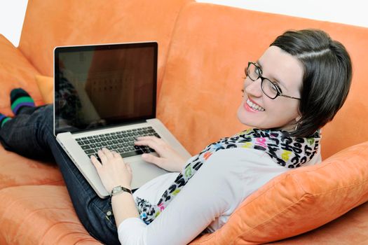 young business woman in casual clothes working on laptop computer on orange sofa isolated on white