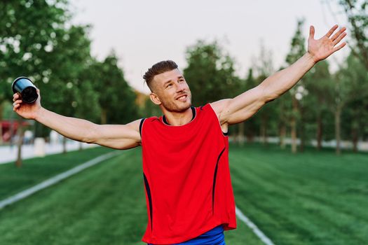 Cheerful sporty man in the park on green grass doing exercises. High quality photo