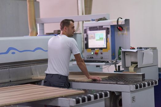 Young worker works in a factory for the production of wooden furniture