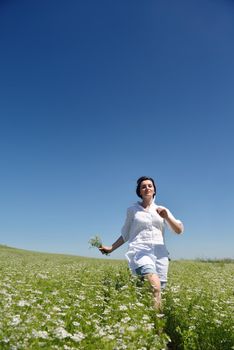 Young happy woman in green field with blue sky in background