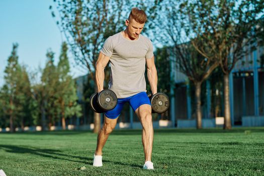 athletic man training with dumbbells in the morning Park. High quality photo