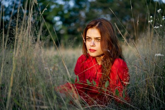 woman in a red dress lies on the grass in the field nature fashion. High quality photo