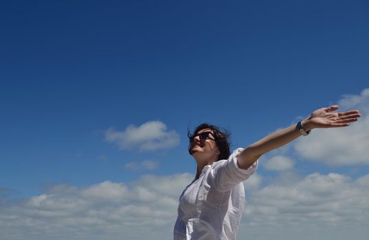 Happy  young woman with spreading arms, blue sky with clouds in background  - copyspace