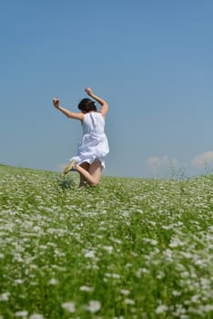 Young happy woman in green field with blue sky in background