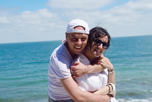 Smiling happy couple looking at camera together at summer beach