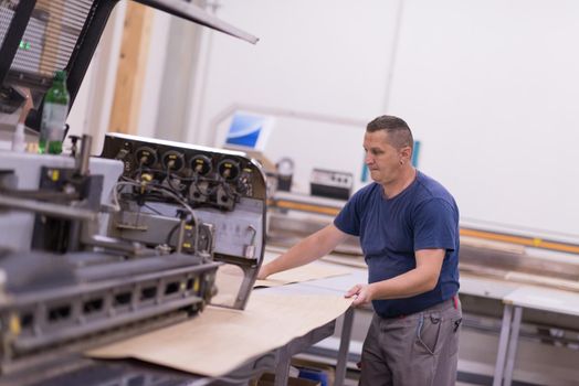 Young worker works in a factory for the production of wooden furniture