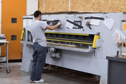 Young worker works in a factory for the production of wooden furniture