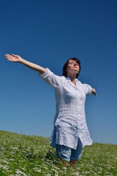 Young happy woman in green field with blue sky in background