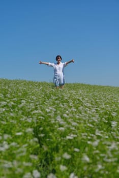 Young happy woman in green field with blue sky in background