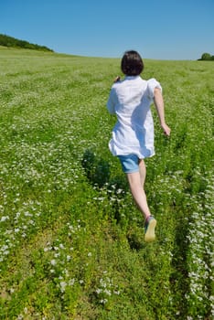 Young happy woman in green field with blue sky in background