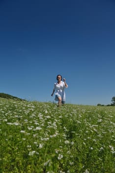 Young happy woman in green field with blue sky in background