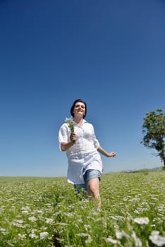 Young happy woman in green field with blue sky in background