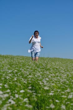 Young happy woman in green field with blue sky in background