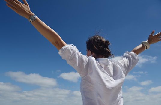 Happy  young woman with spreading arms, blue sky with clouds in background  - copyspace